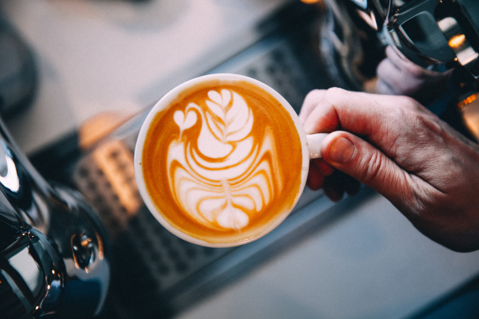 A barista holding a flat white