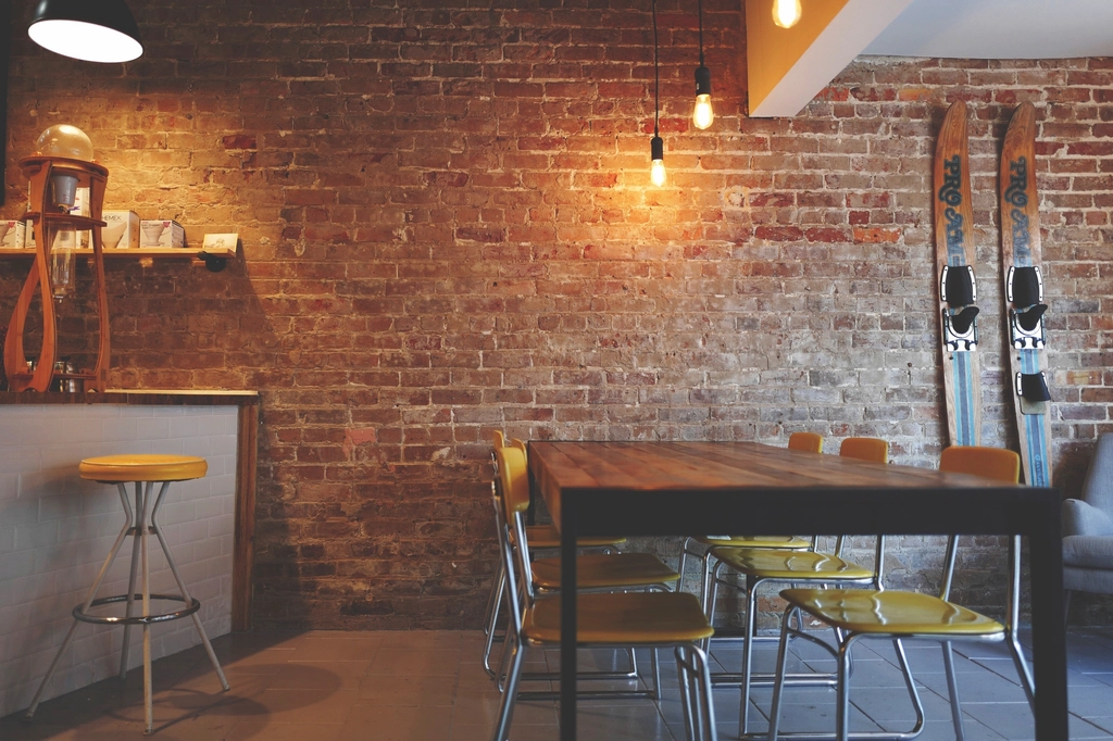 A café interior with a brick wall, timber table and bar stools